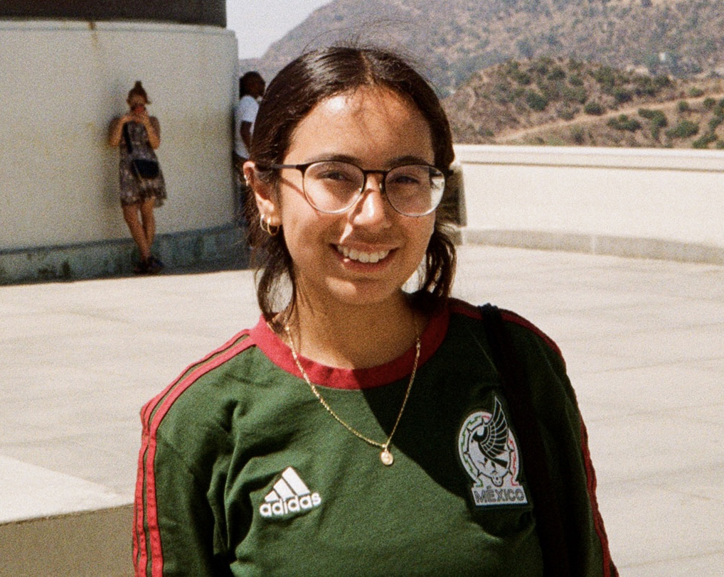 A woman smiling at the camera with a mountain range in the back.