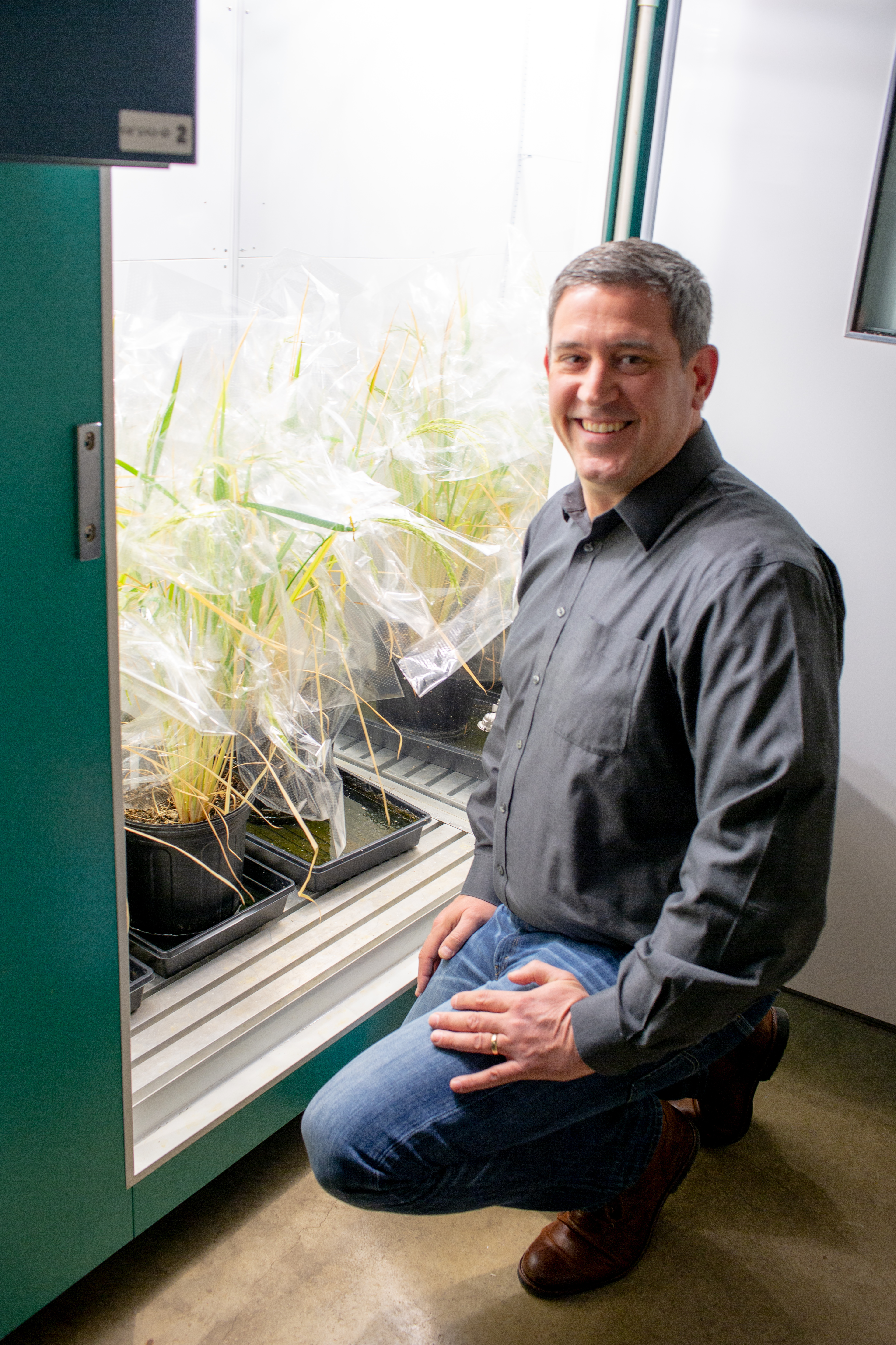 Carl Bernacchi kneeling in front of a refrigerator with plant samples in it.