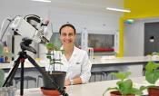 Elizabete Carmo-Silva stands at a lab bench with a LICOR machine measuring the photosynthetic efficiency of plants