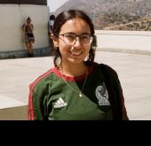 A woman smiling at the camera with a mountain range in the back.